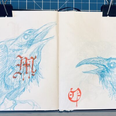 Pages from a sketchbook, with drawings of crows in blue pencil, with gothic-style letters drawn over them.